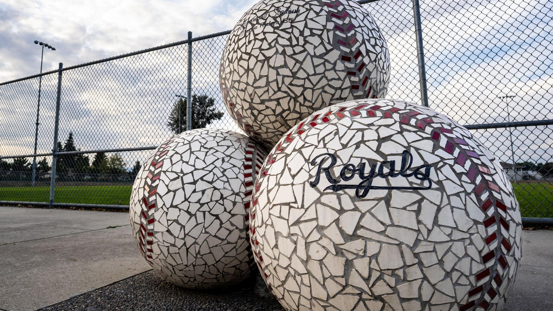3 mosaic baseballs stacked in front of a ball park.